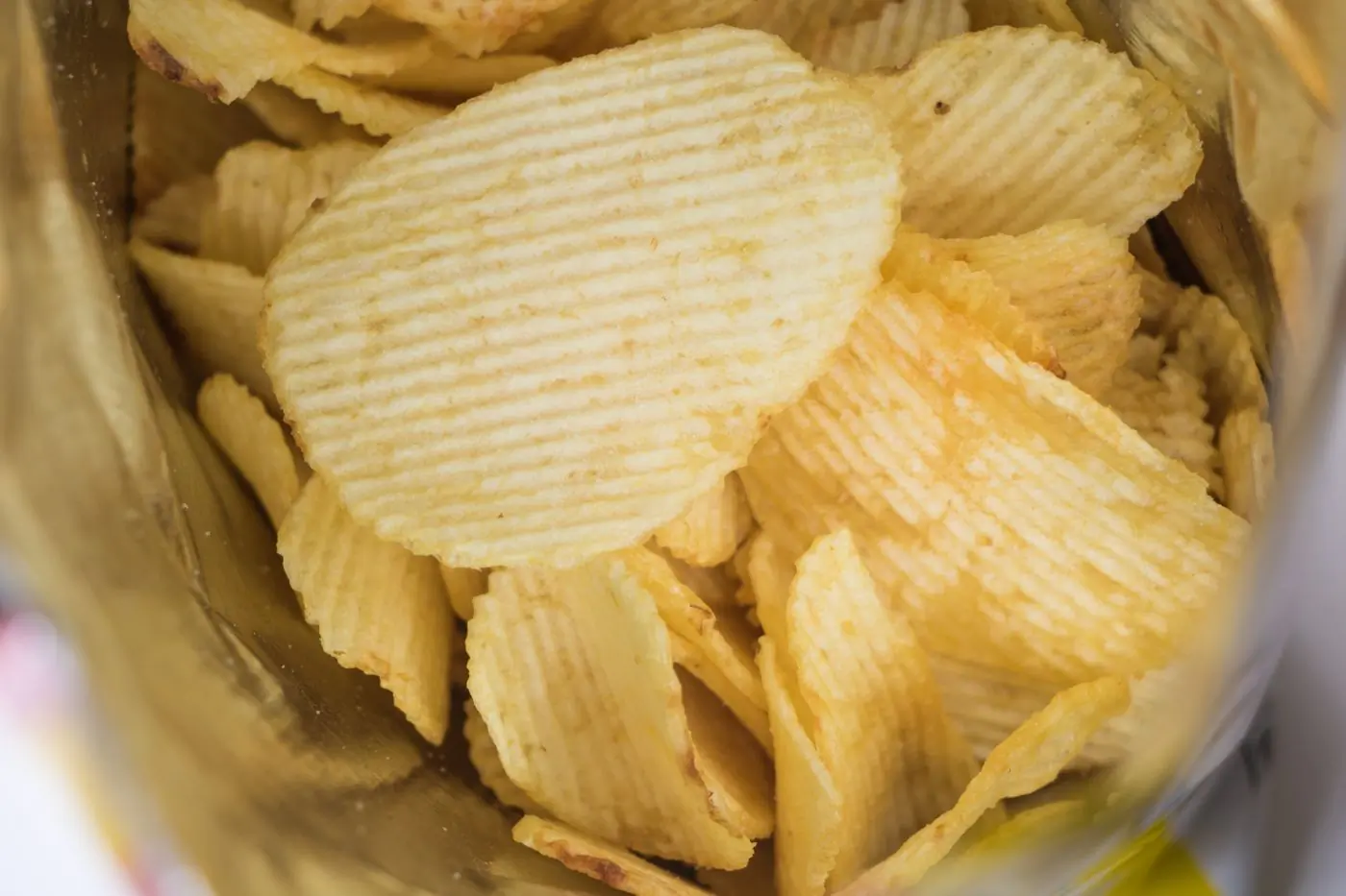 A single ridged chip held up at the mouth of an open bag