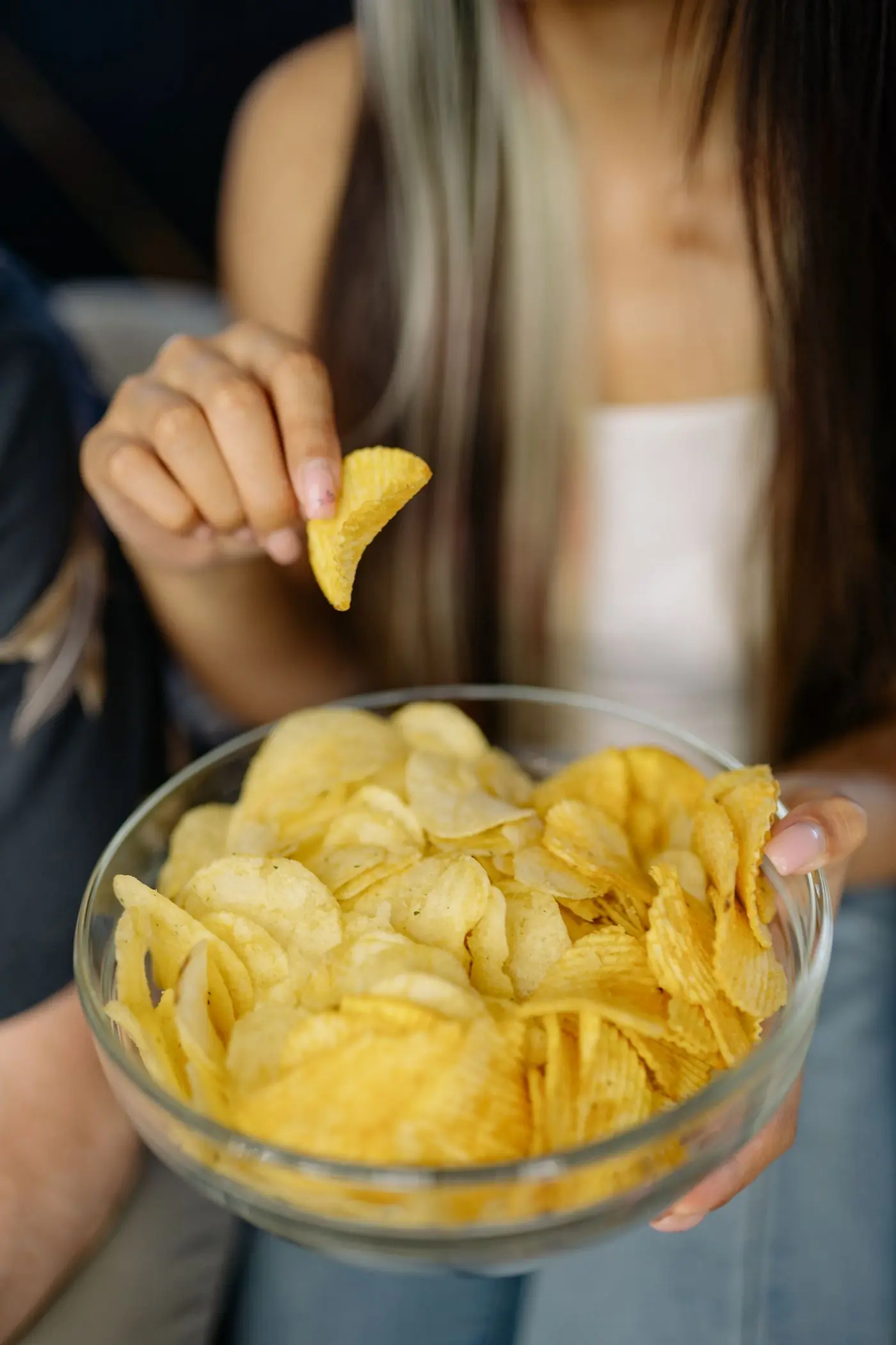 A woman picking a chip from a glass bowl