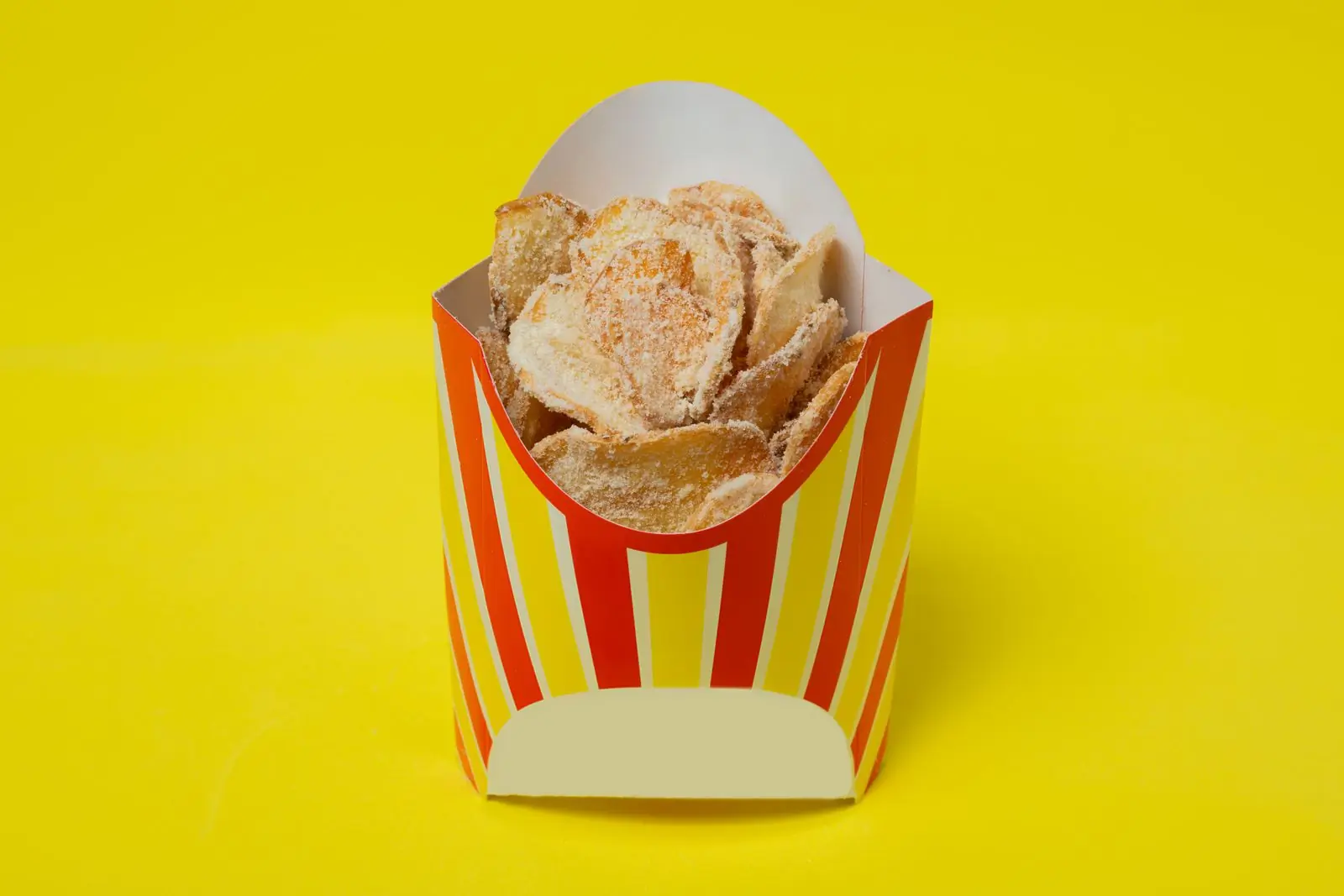 A striped carton of chips on a vivid yellow ground