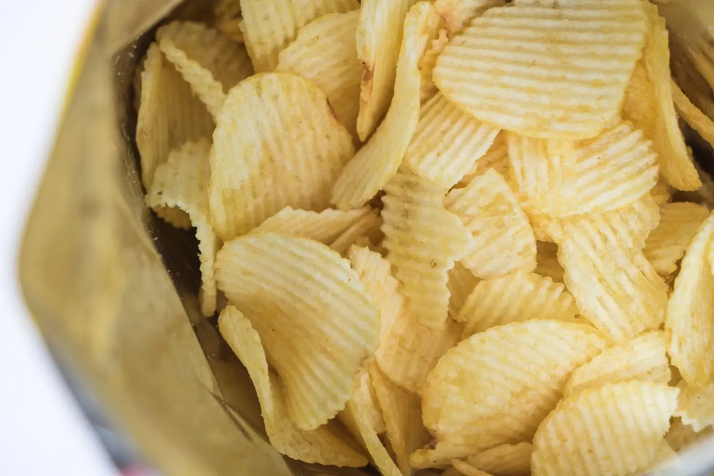 Looking down into an open bag of golden ridged chips