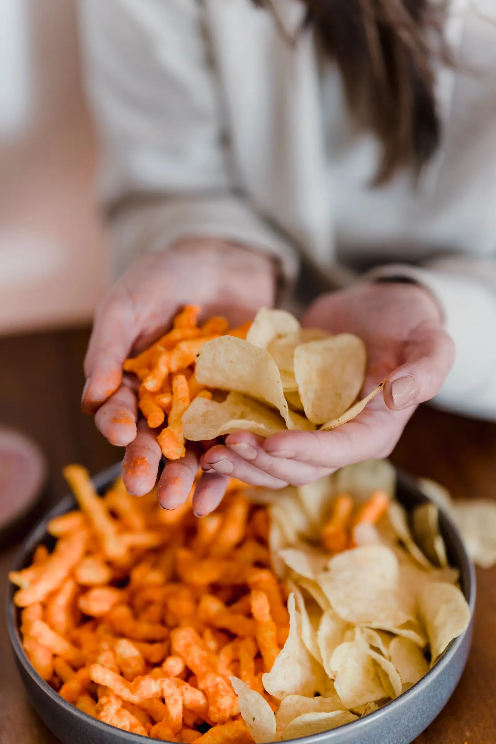 Two hands sharing a heap of chips over a party bowl