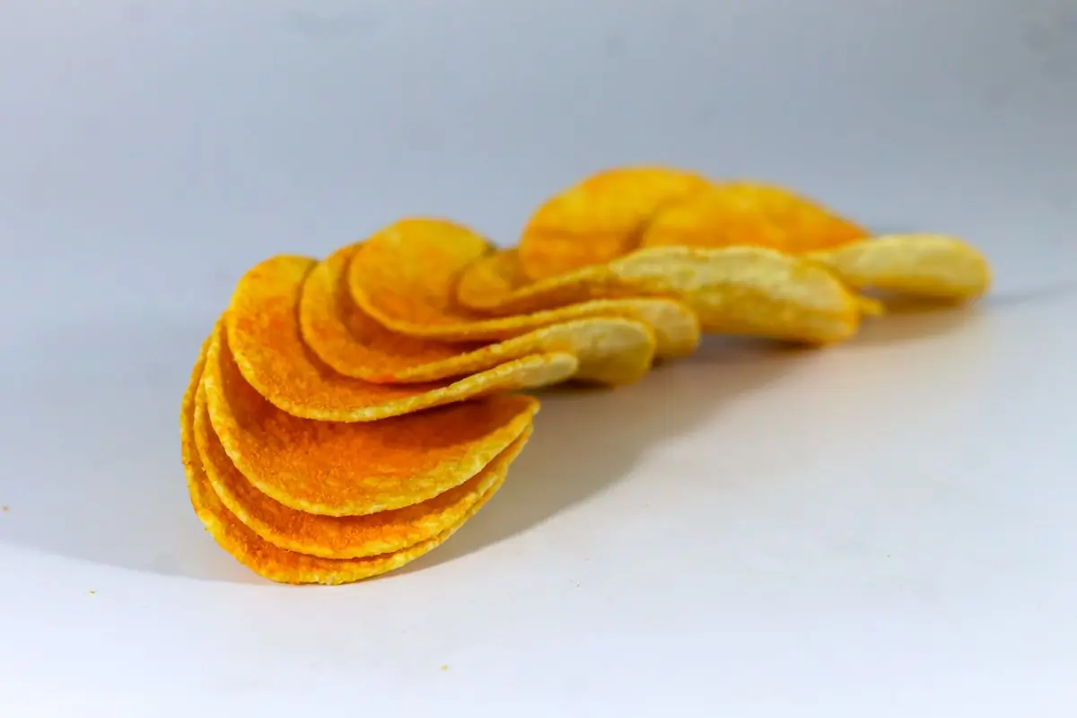 An arc of paprika-orange seasoned chips cascading against a white ground