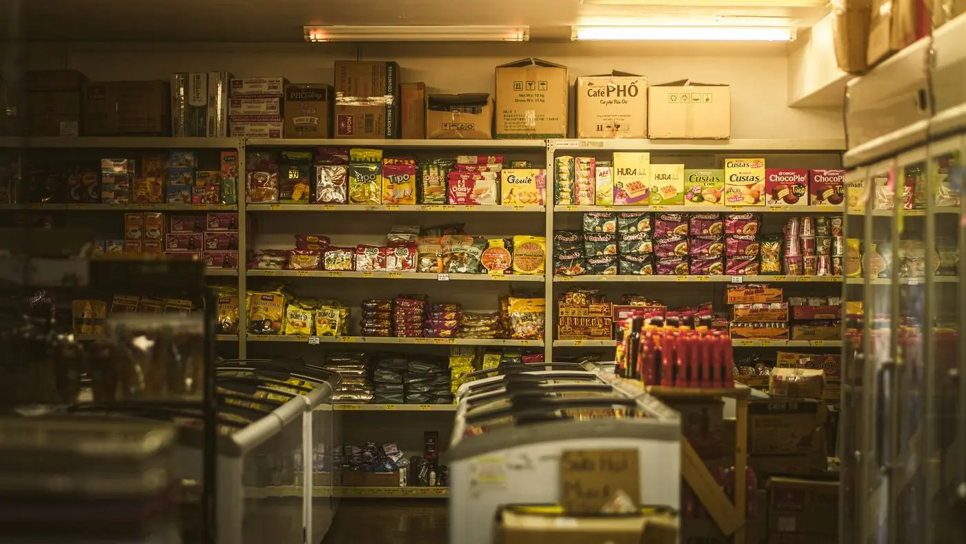 The warm amber-lit interior of a corner shop after dark