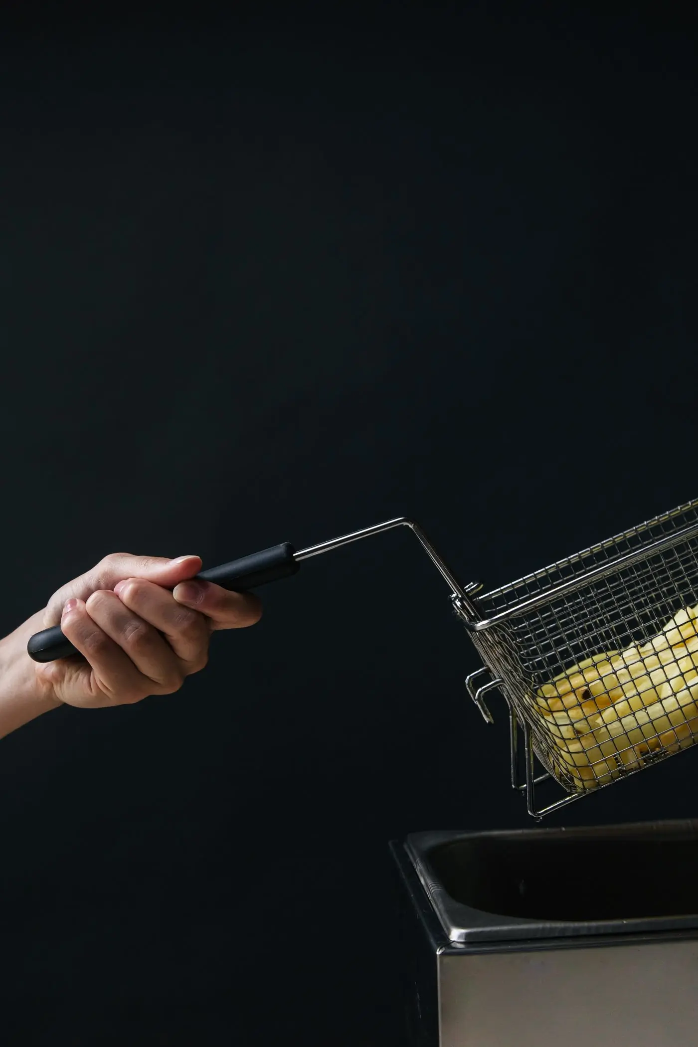 An outstretched arm holding up a wire basket against a pure black background