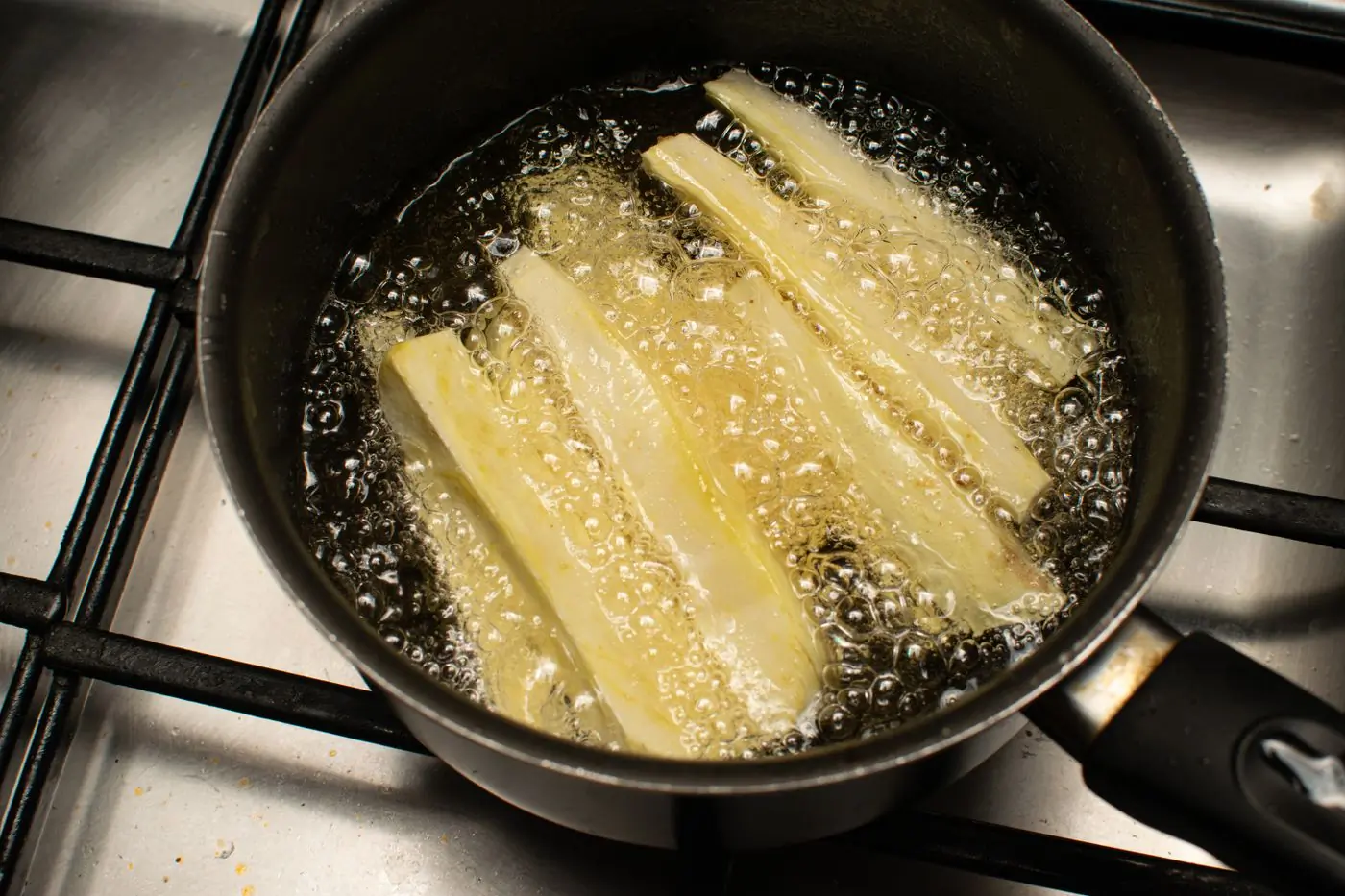 Golden sticks tumbling in a hot black kettle pan
