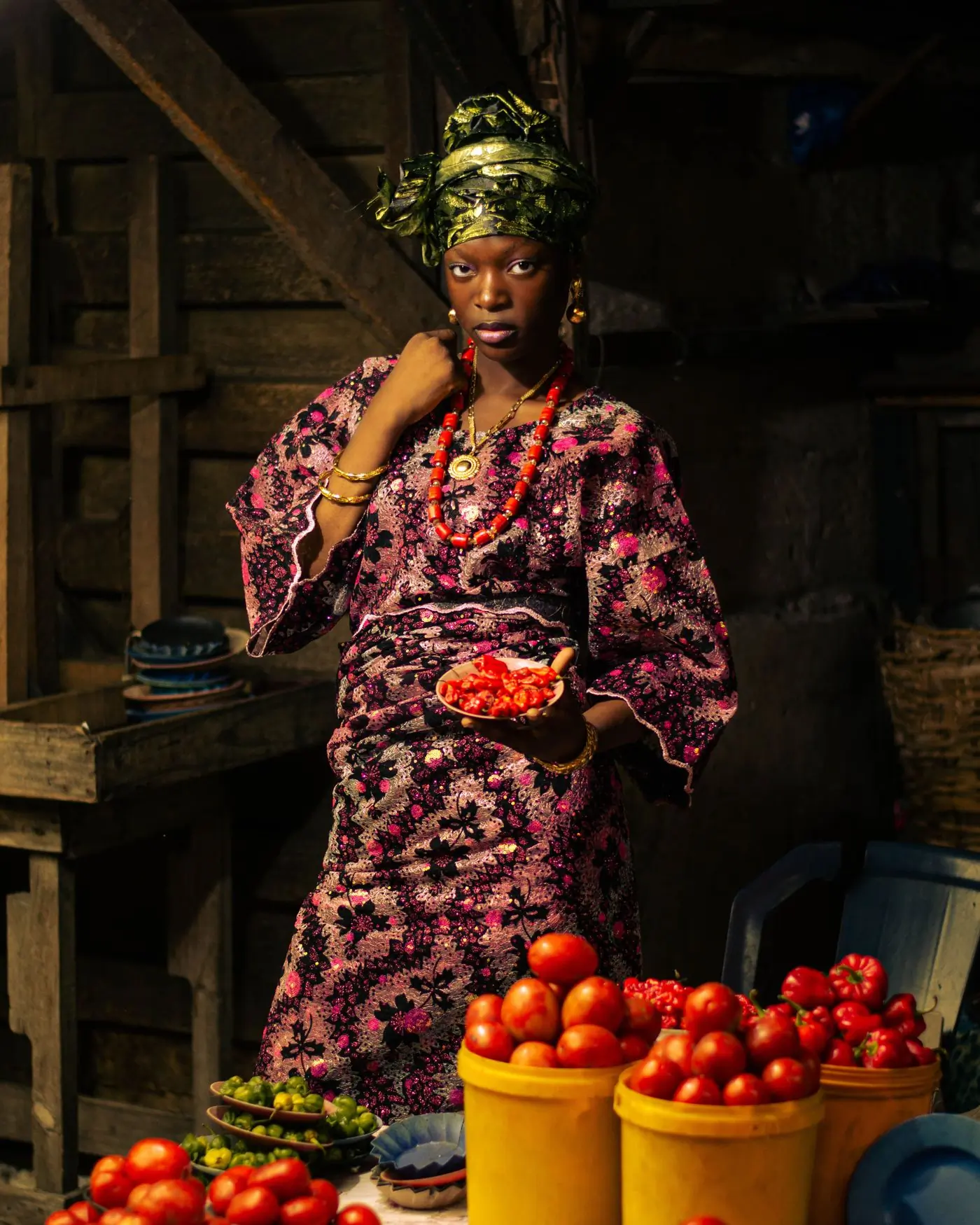 A market trader holding fresh peppers above a heap of tomatoes