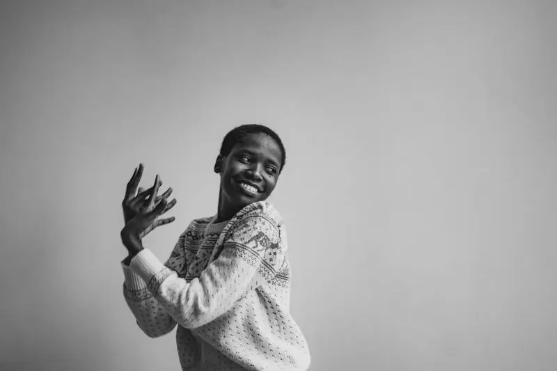 A woman in a cream sweater laughing, photographed in black and white