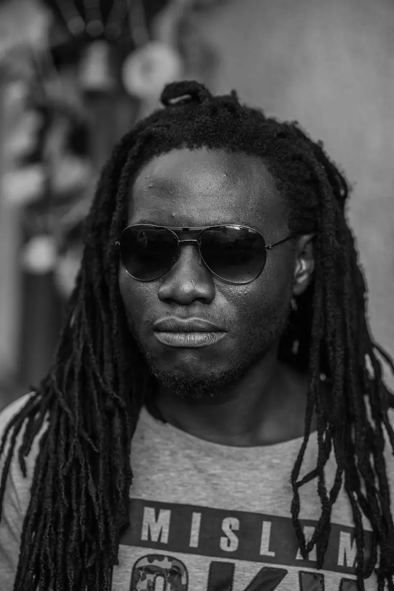 A man with long locs and sunglasses photographed in black and white