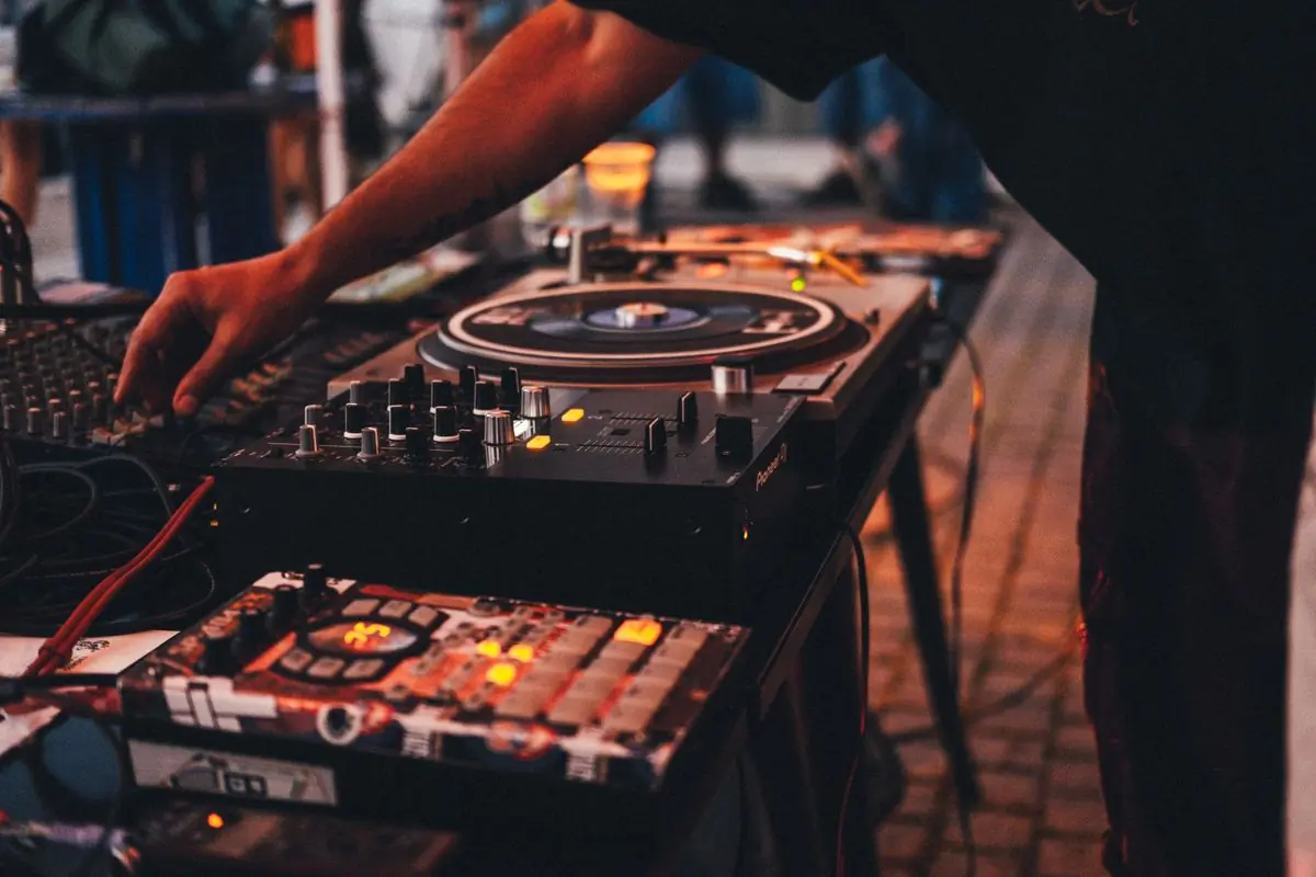 A pair of turntables and a mixer lit in warm light at an outdoor event