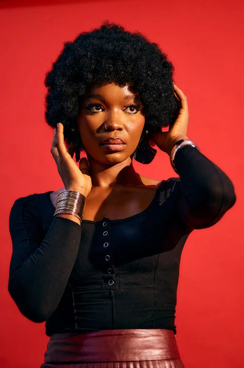A singer in silver rings photographed against a red ground