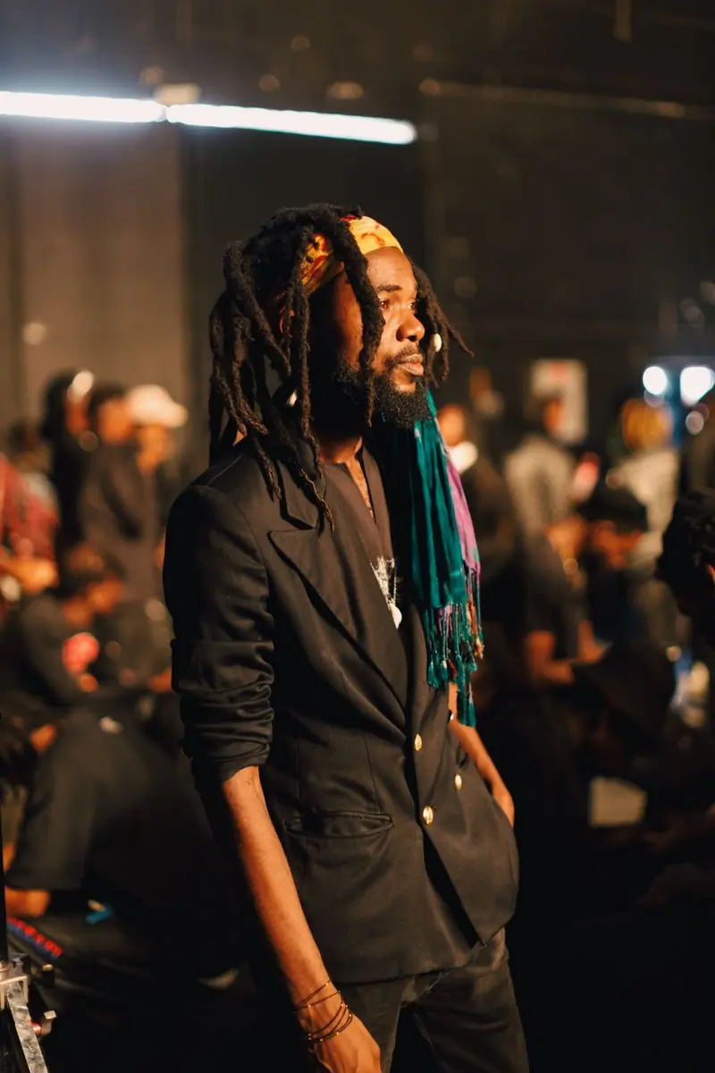 A musician with locs in a patterned jacket at a live event