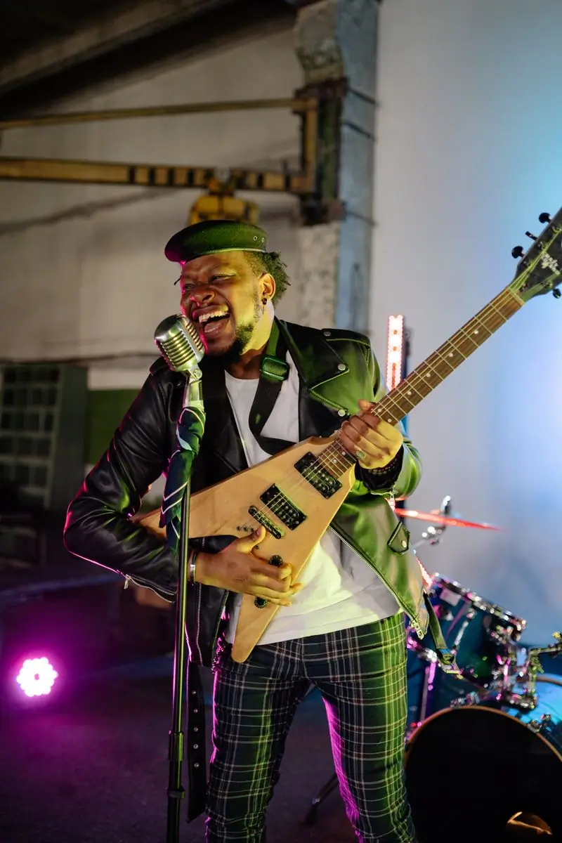 A guitarist laughing mid-song with a bass slung across him