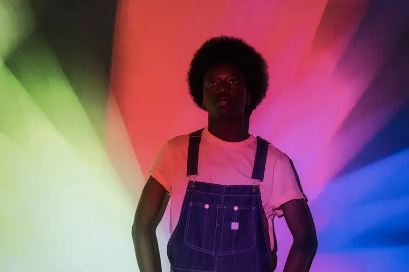 A man with an afro lit by coloured stage projections