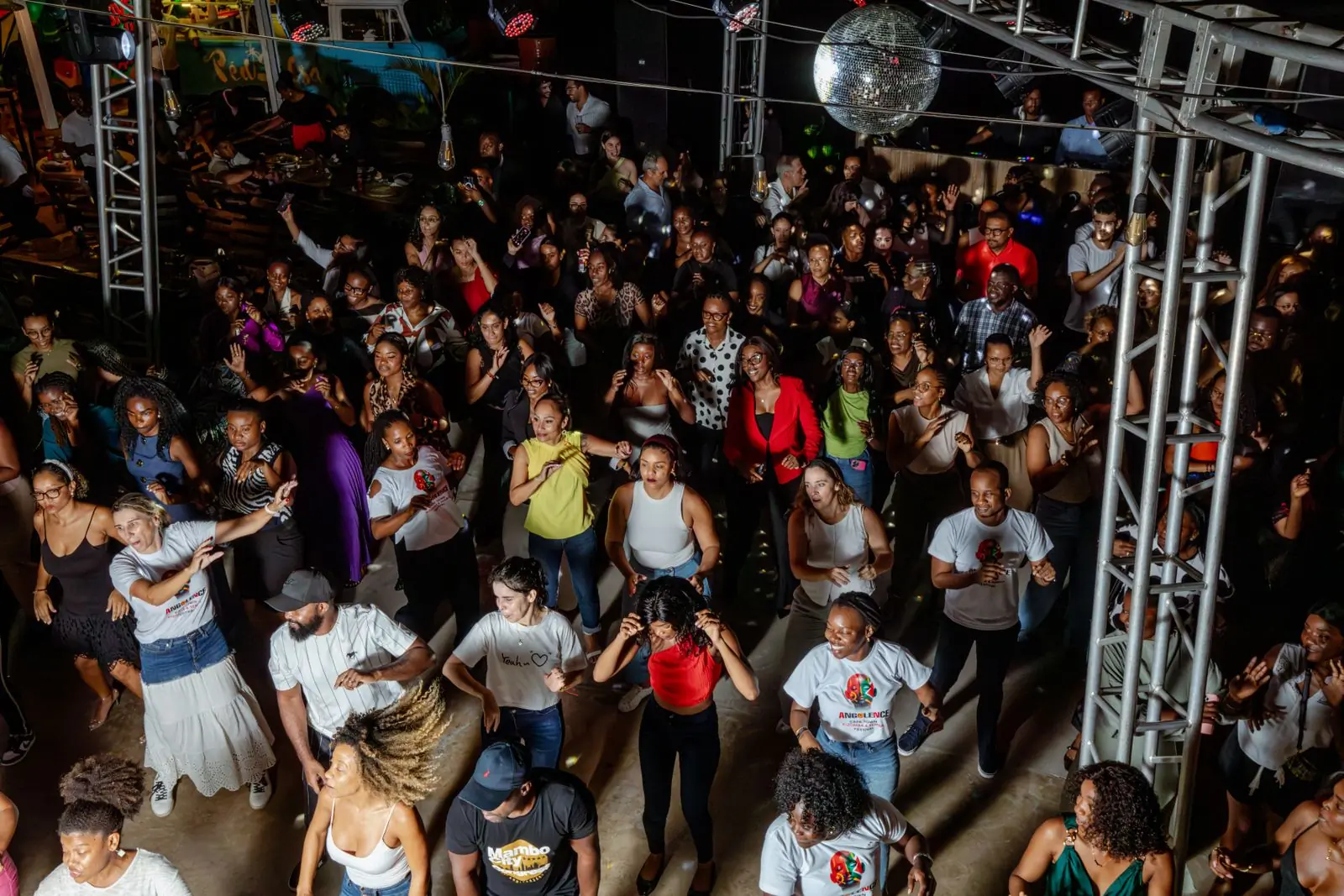 A crowd dancing under a mirror ball in a covered venue