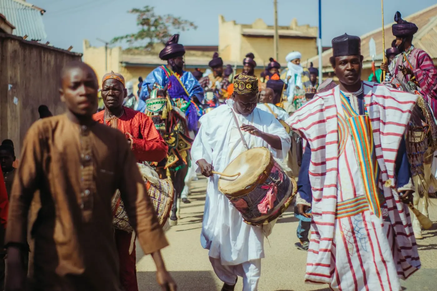 A street parade in bright dress passing the festival site