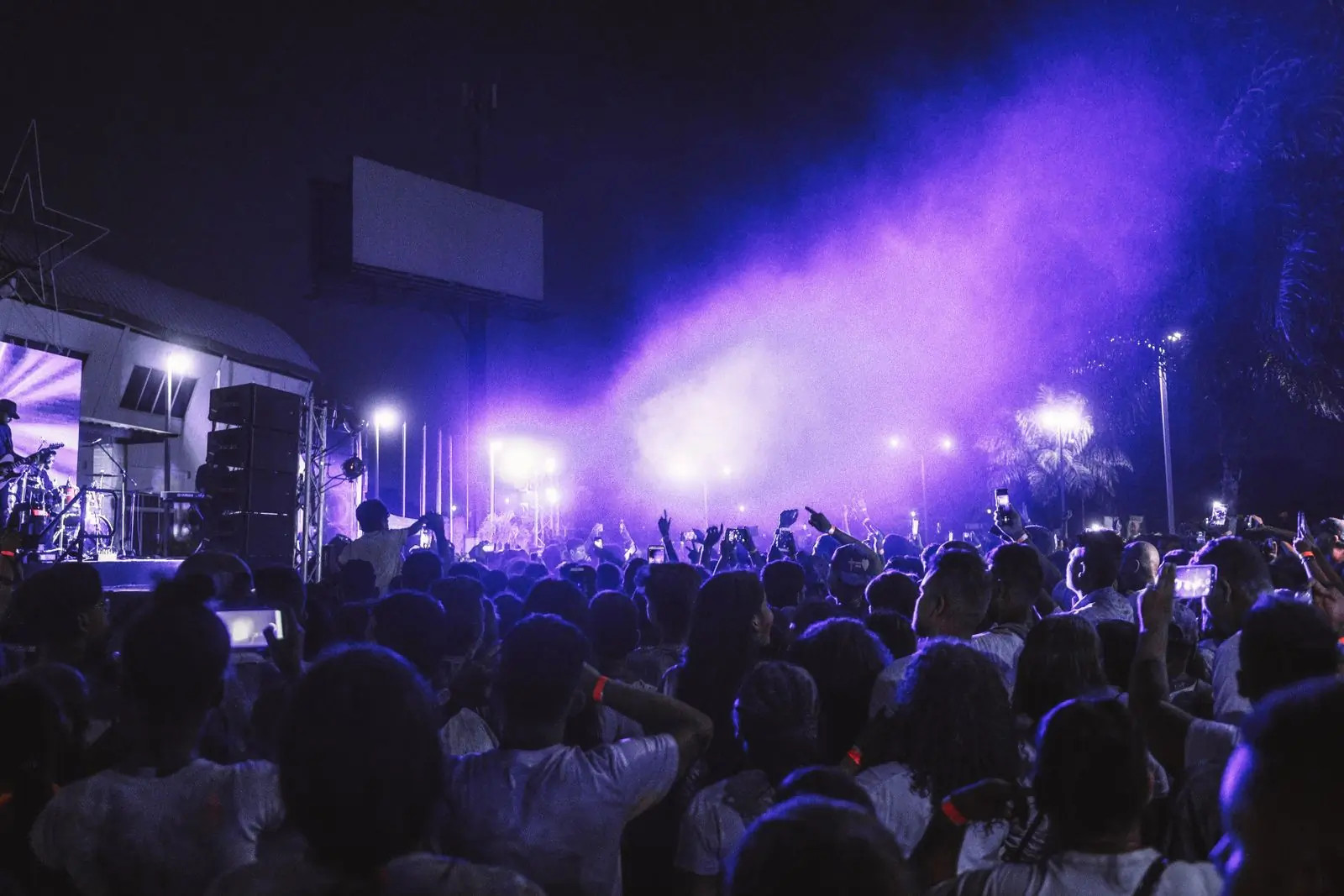 The festival site at night with the stage lit behind the crowd