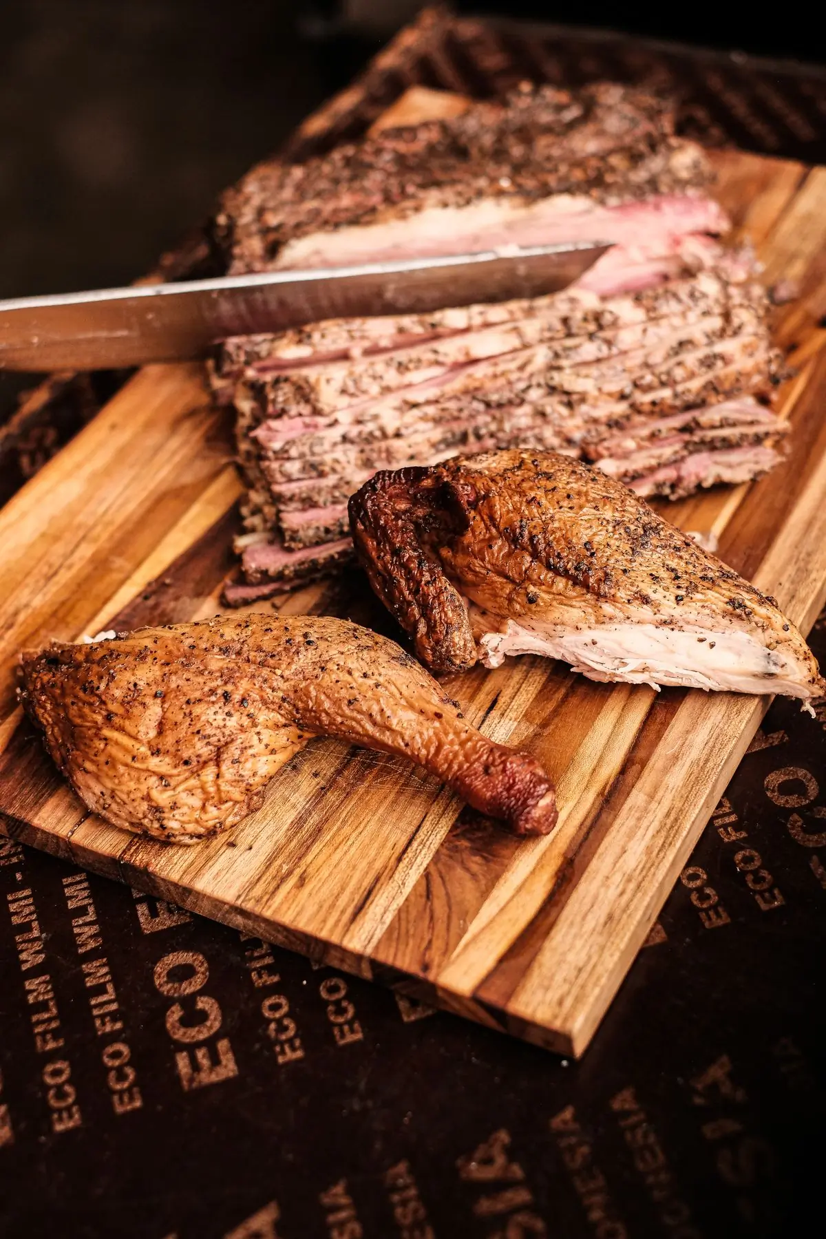 Smoked brisket and half a chicken on a carving board