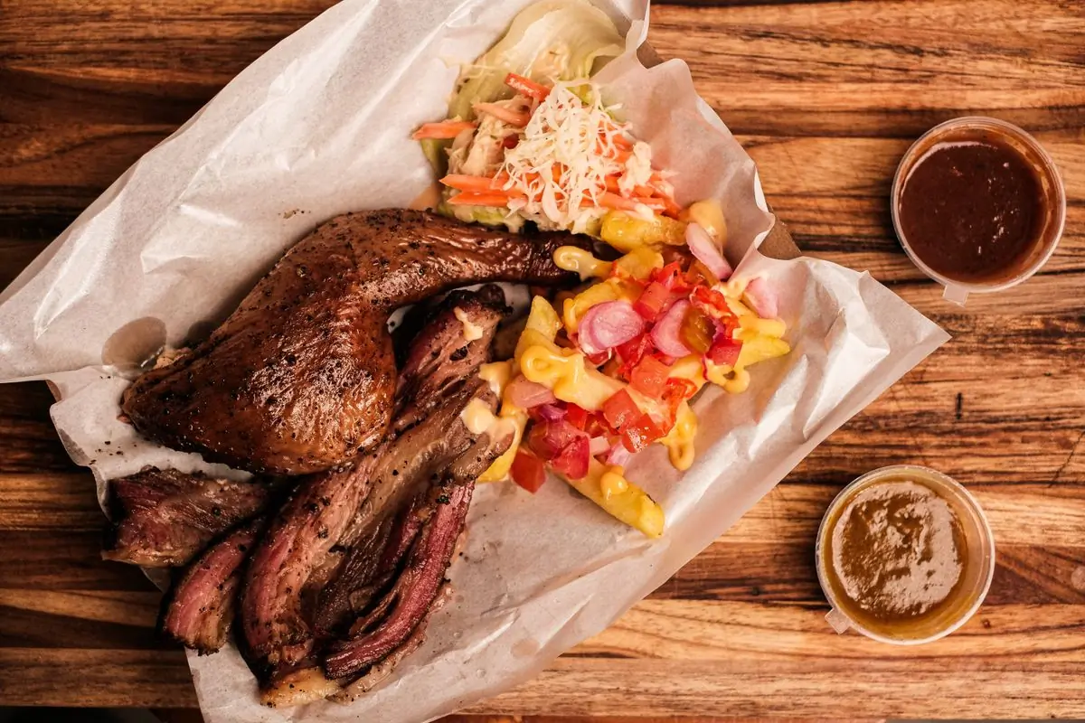 A barbecue platter of smoked meats laid out with sides