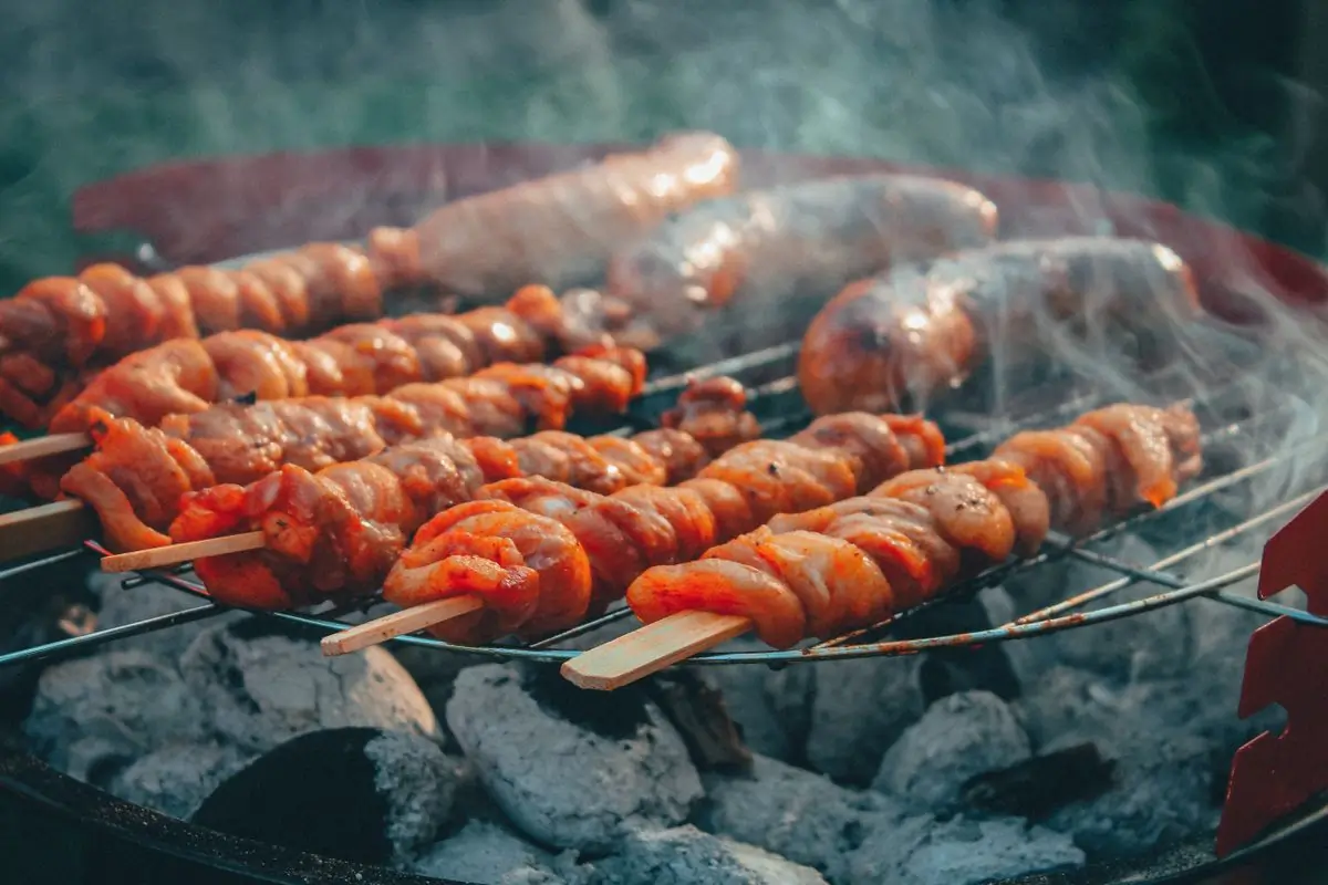 Skewers and sausages turning over charcoal