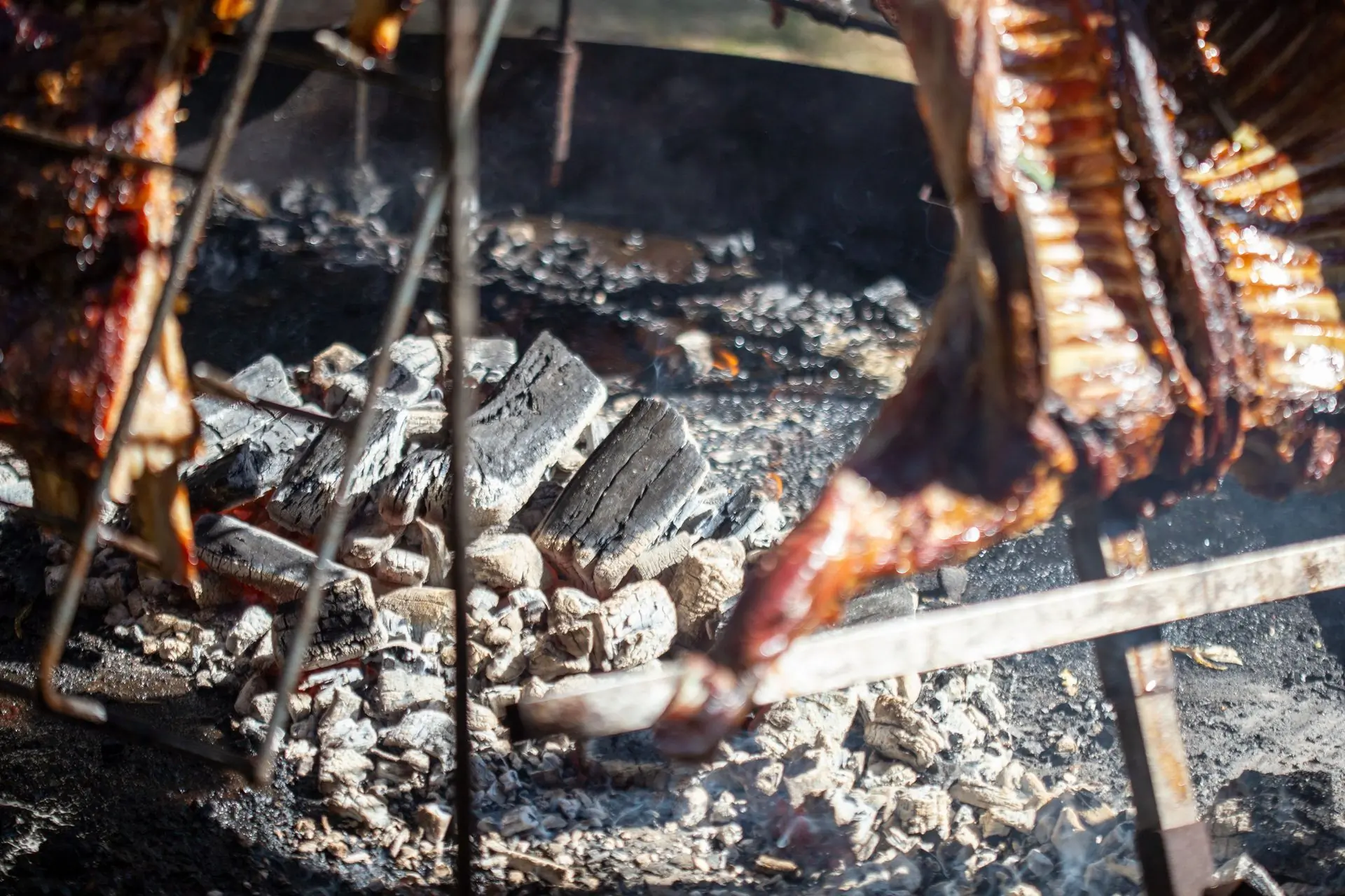 Meat smoking over glowing hardwood coals