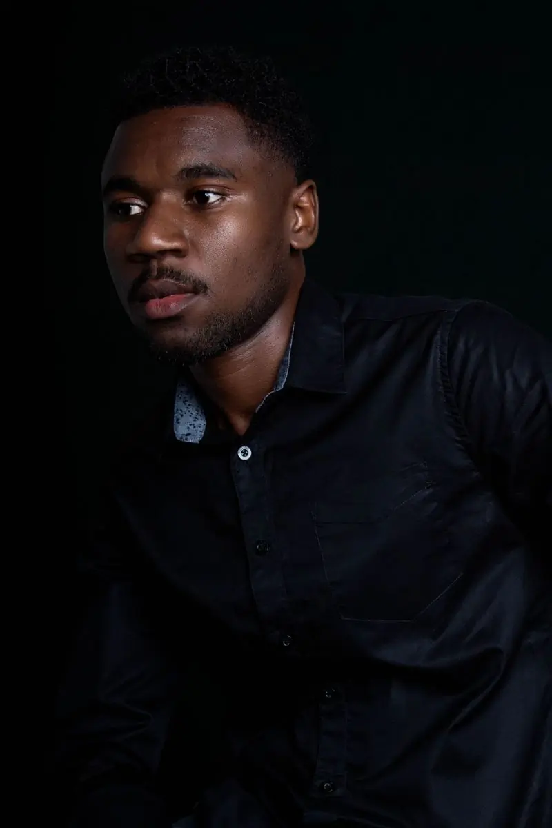 Kojo Danquah, a guest, photographed against a dark ground