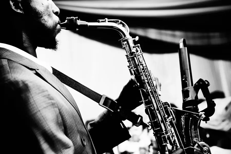 A saxophonist in performance, photographed in black and white