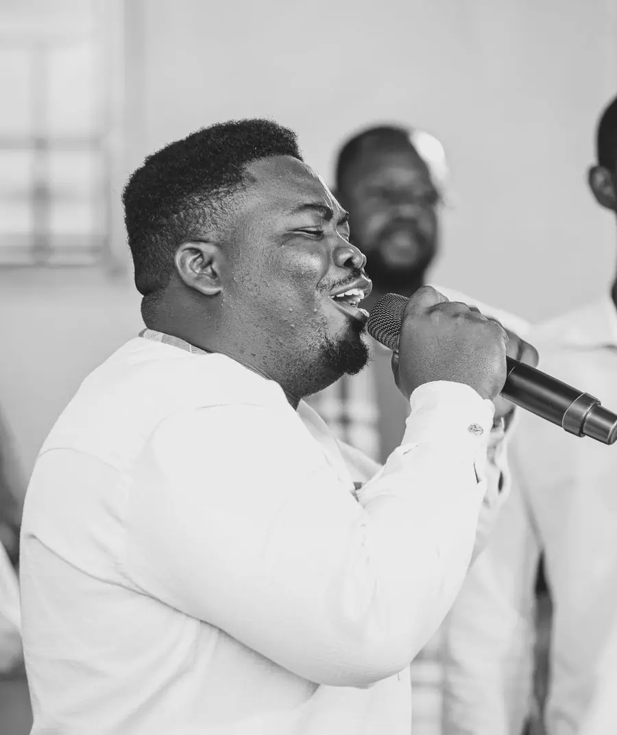 A singer performing into a microphone, photographed in black and white