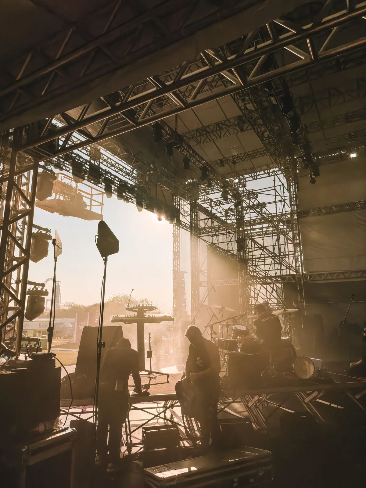 Musicians silhouetted on an outdoor stage at sunset