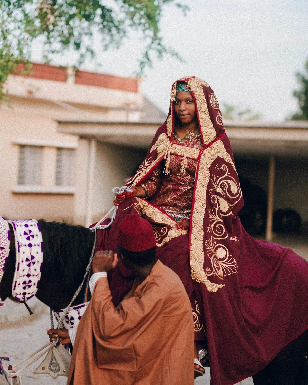 A bride in deep red traditional attire at a ceremony