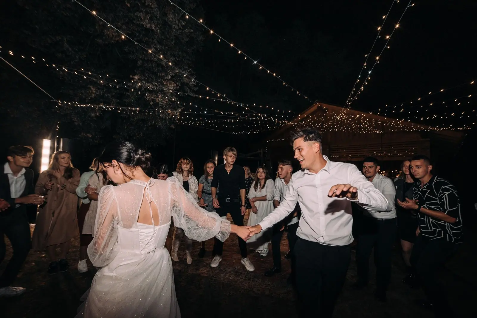 A couple dancing in a crowd under warm lights at night