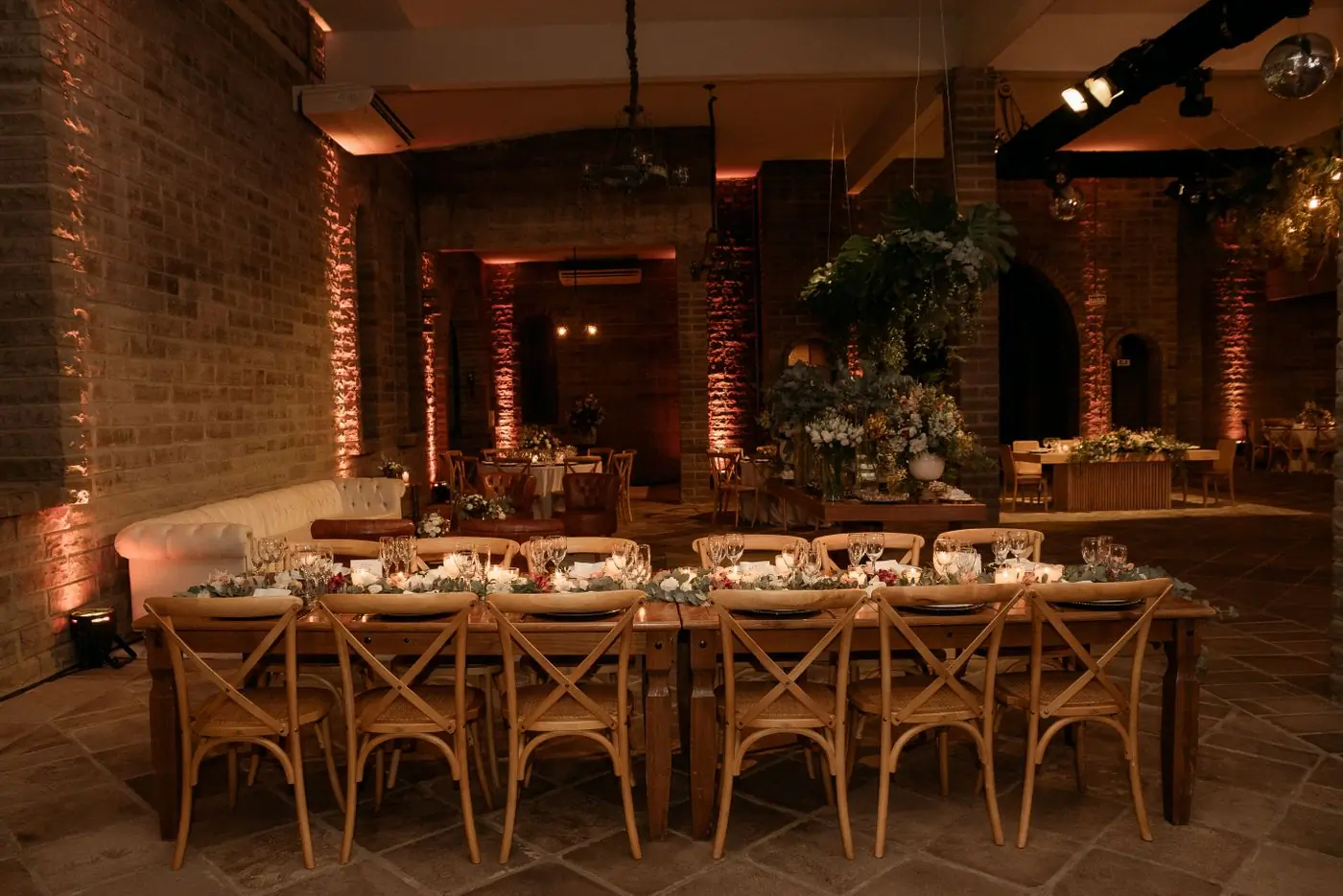 A long banquet table under brick vaults lit in warm amber