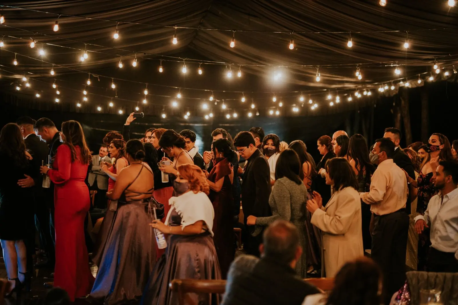Guests dancing under festoon lights at an evening reception