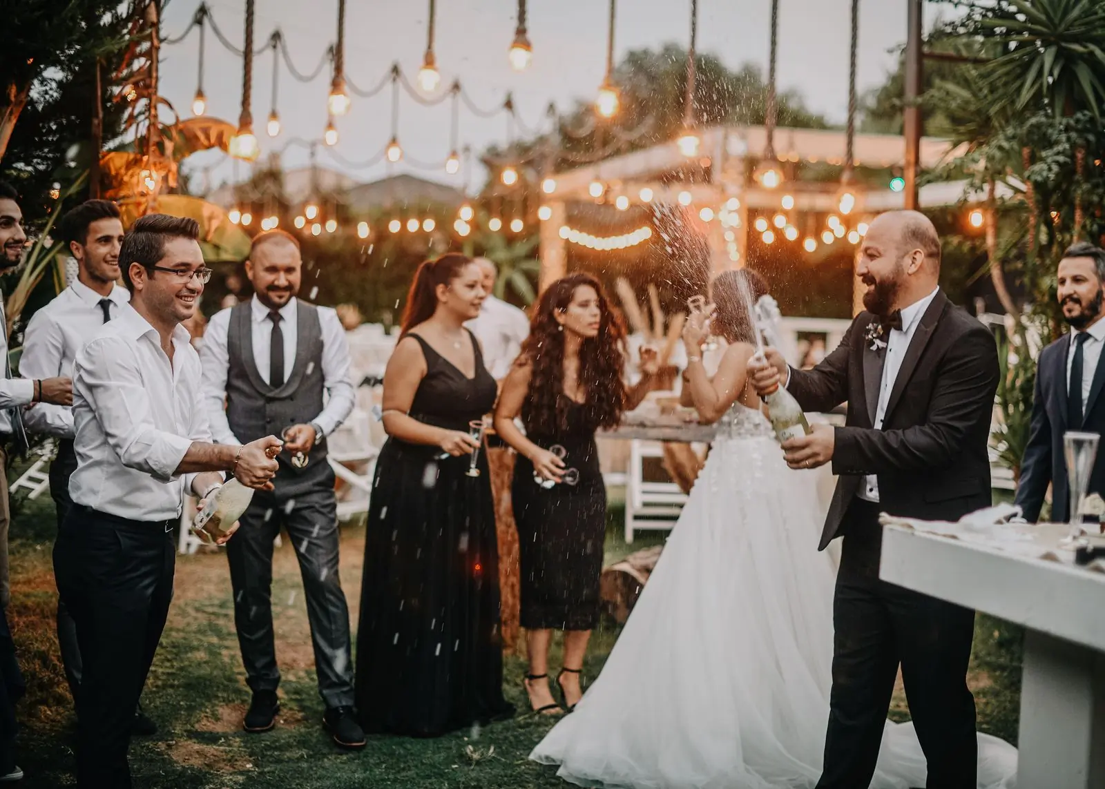 Guests celebrating outdoors under strings of warm light