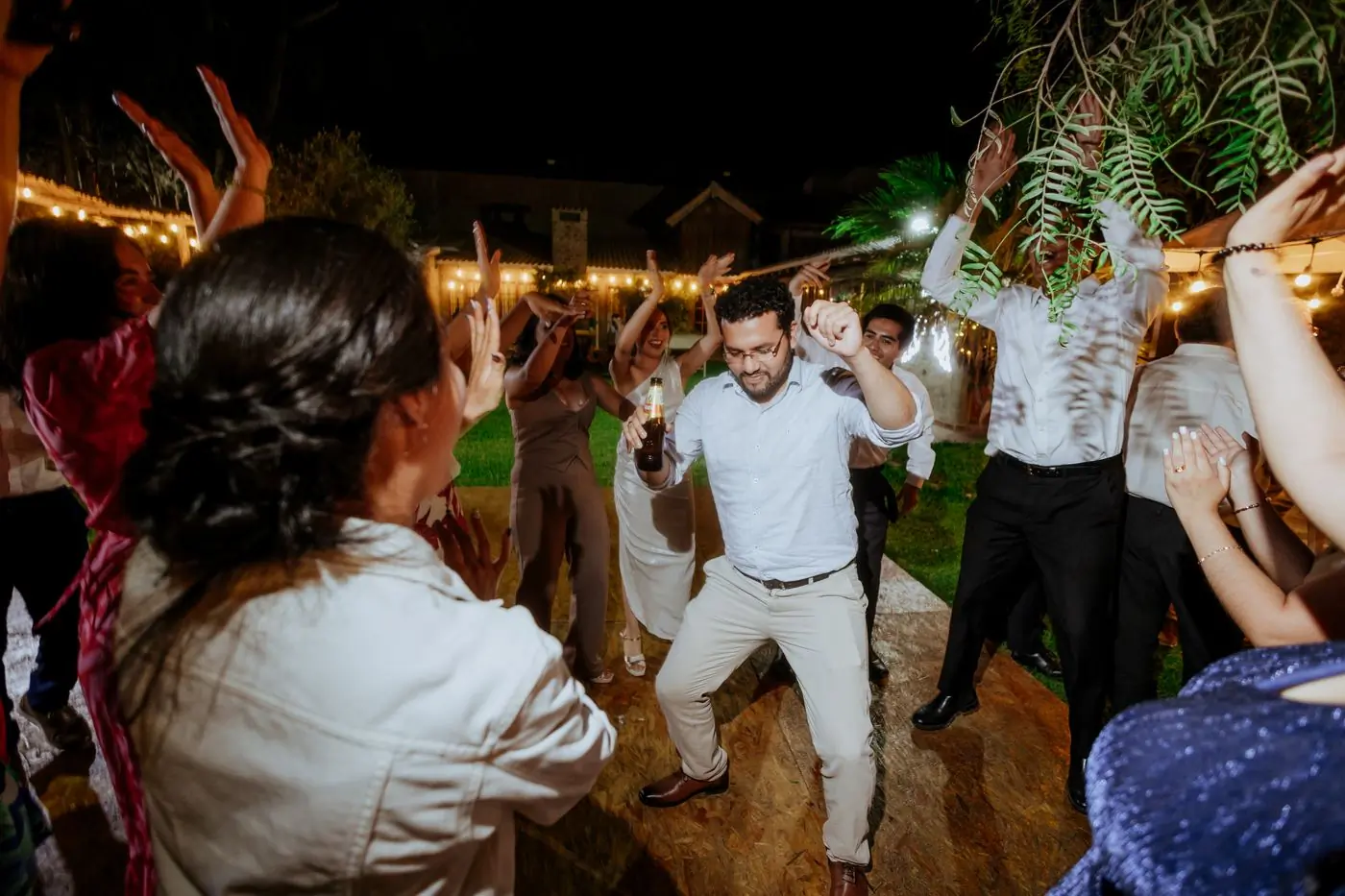 Guests dancing at an outdoor reception under strings of light