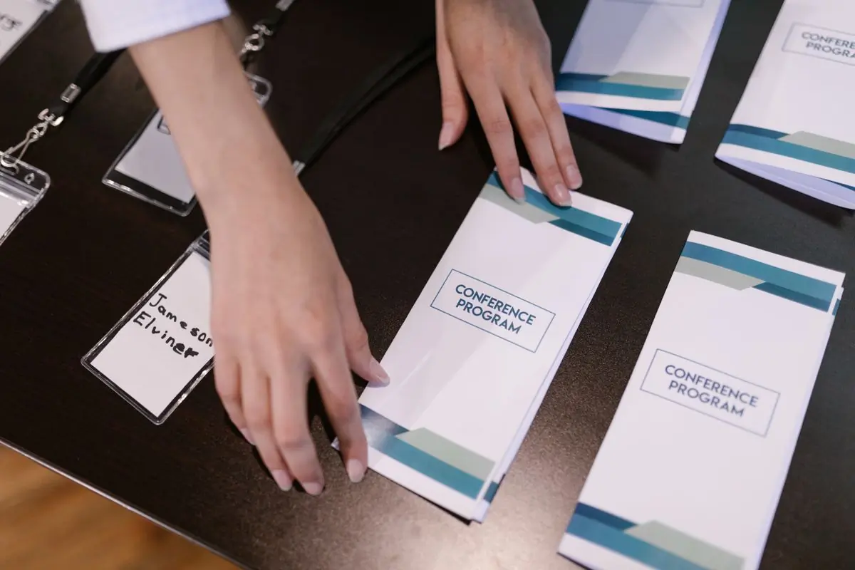 Hands laying out printed programmes at an event desk