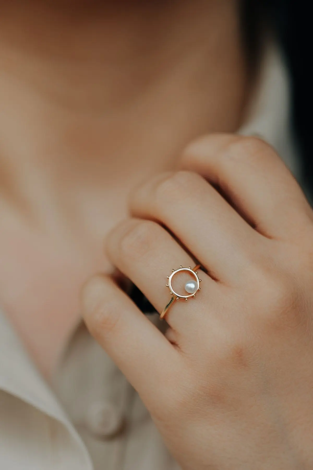 A hand wearing a gold engagement ring, held up to catch the light