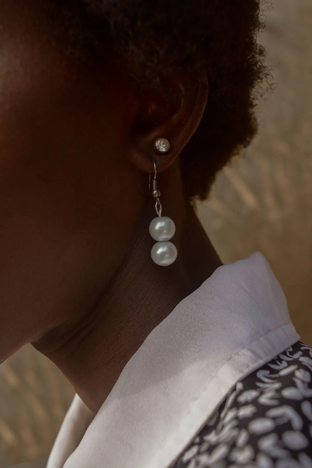 A model in profile wearing fine gold drop earrings