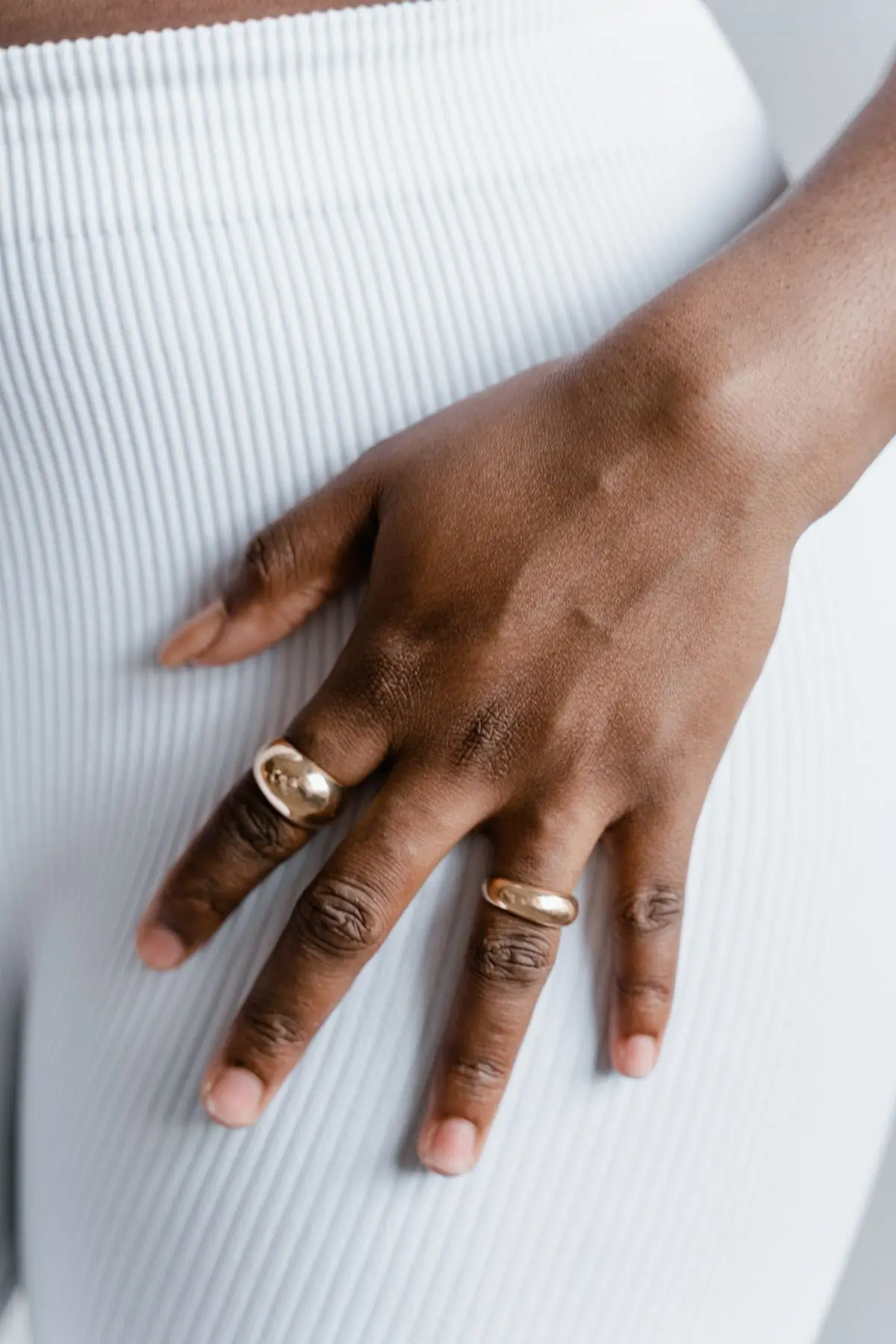 A hand wearing stacked gold rings, photographed close against soft daylight