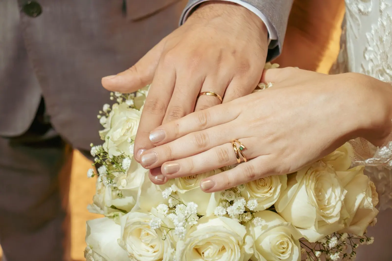 Two hands wearing matched gold wedding bands, held together