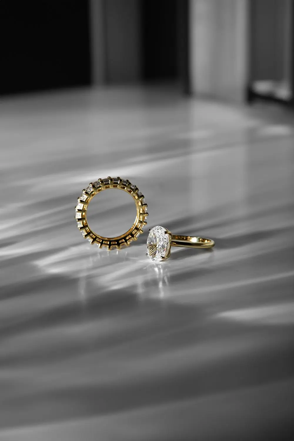 The solitaire and its diamond-set band resting together on a pale daylit surface