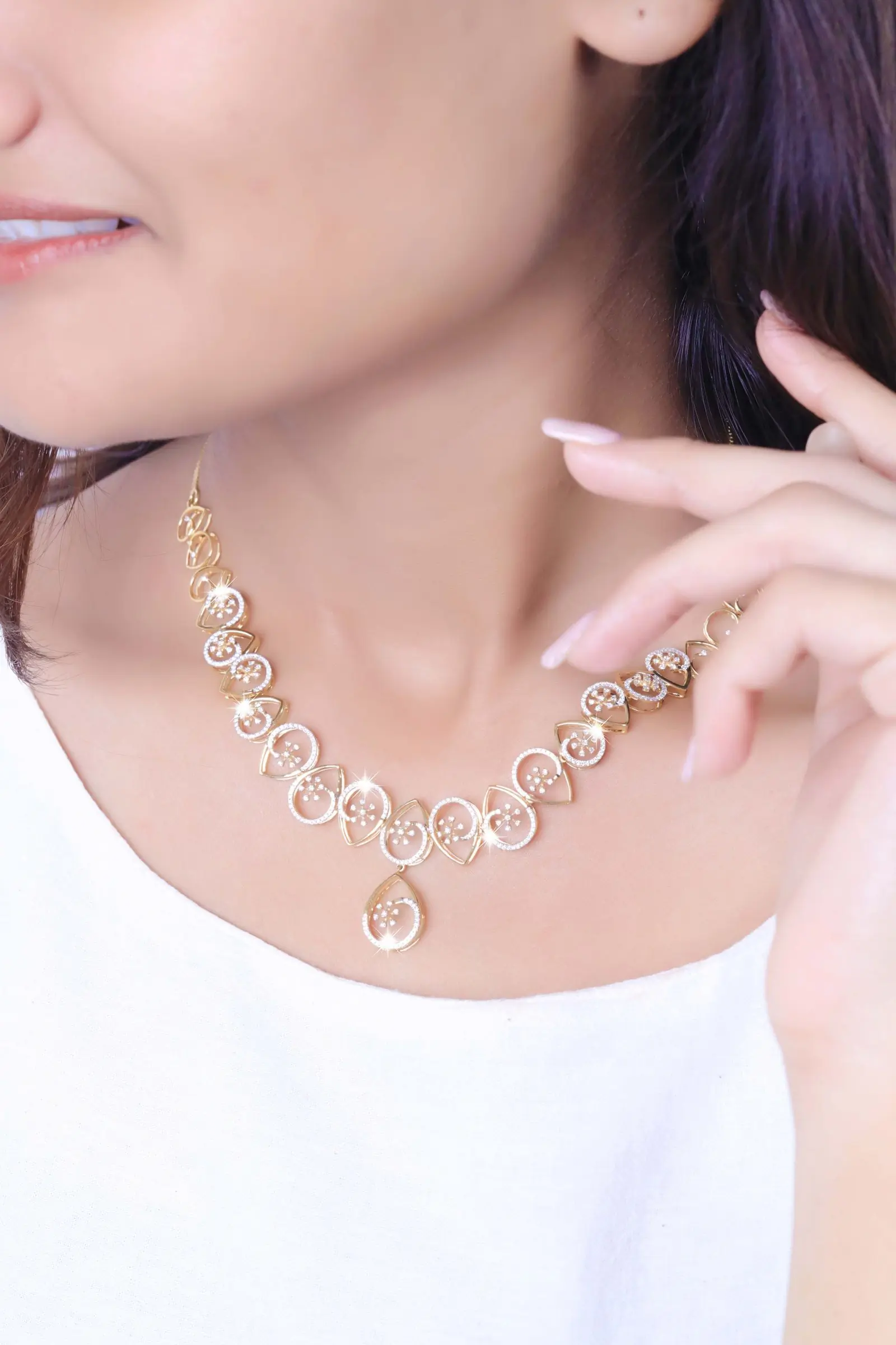 A model in a white top wearing an ornate gold necklace against a soft pale background