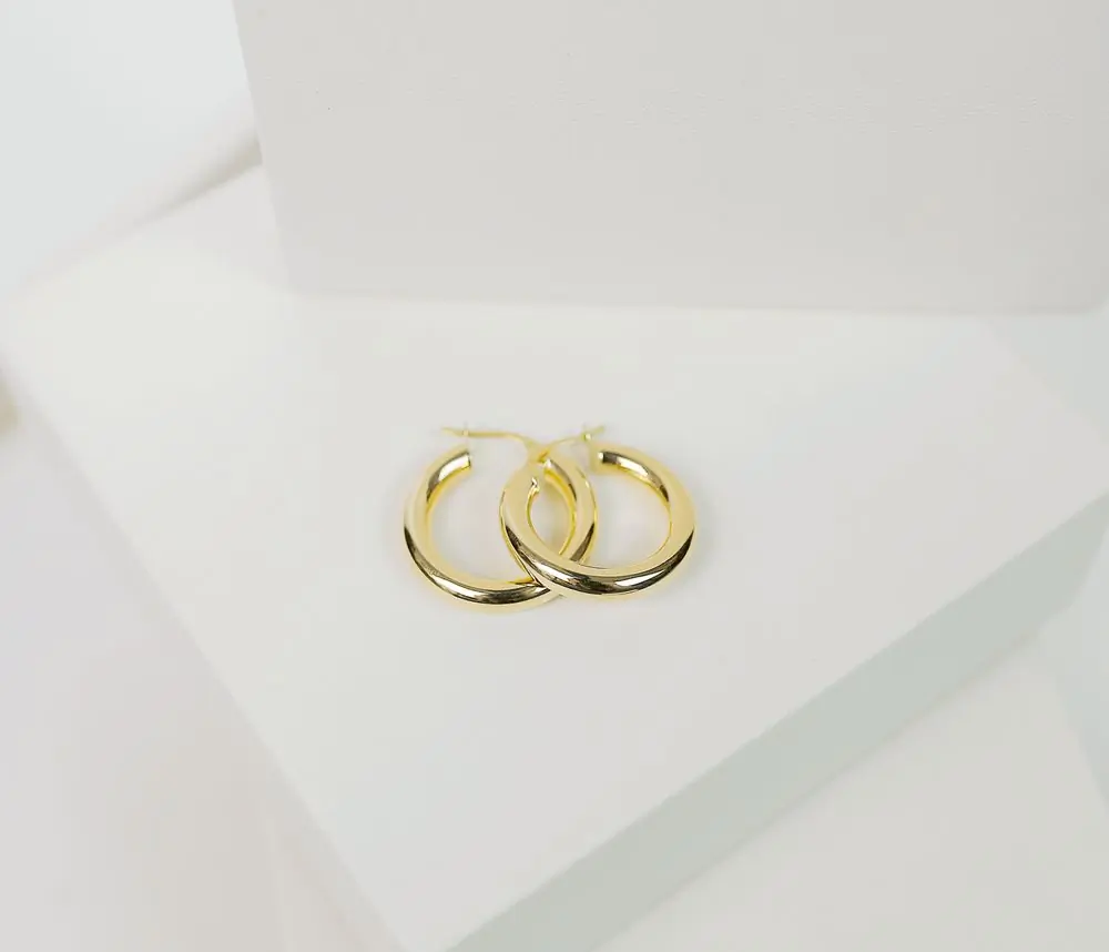 A pair of sculpted gold hoop earrings on a white ground