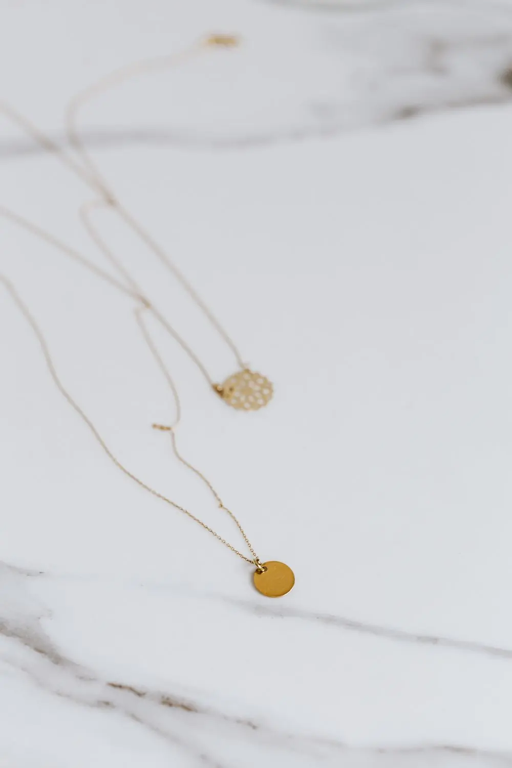 A flat gold herringbone chain necklace on a white ground