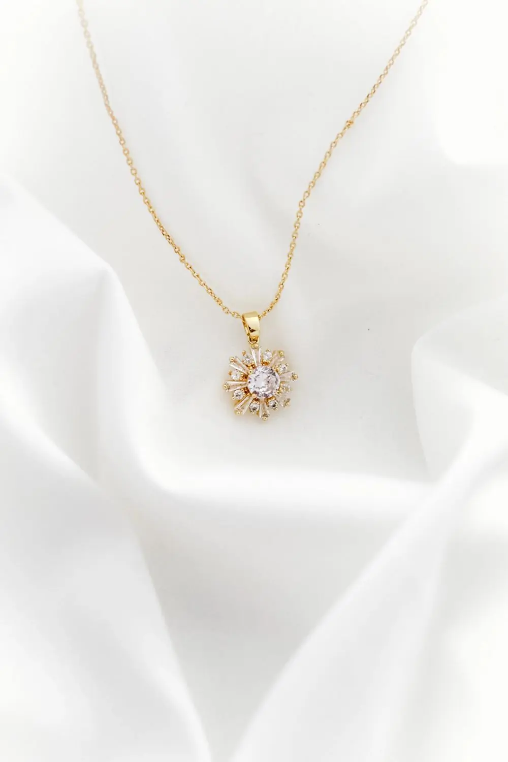 A fine gold necklace with a small pendant, on a white ground