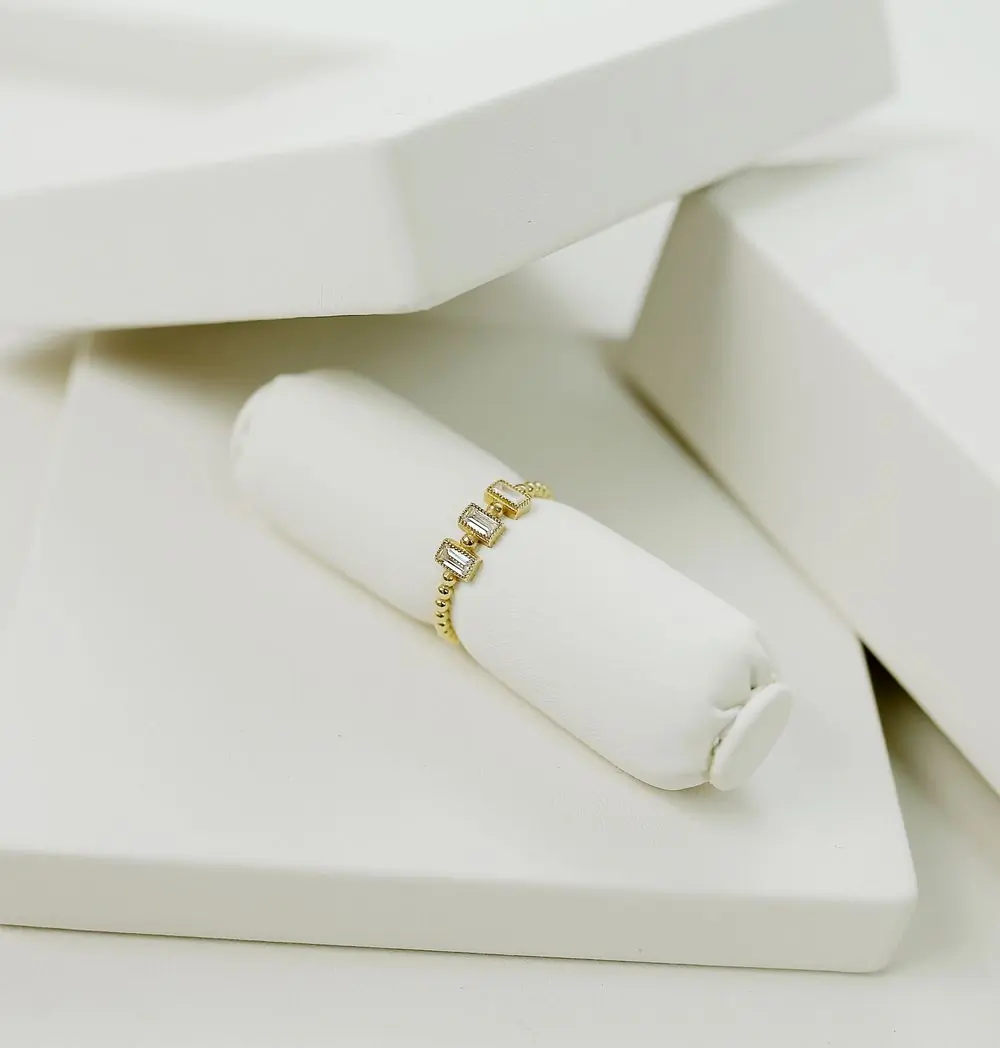A fine gold ring set with three baguette stones, on a white leather display roll