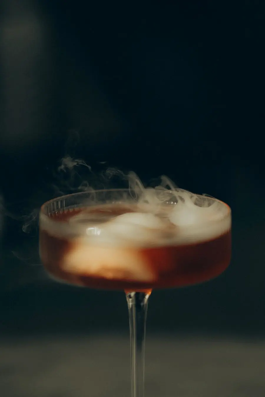 A smoked old fashioned under the bar lamp