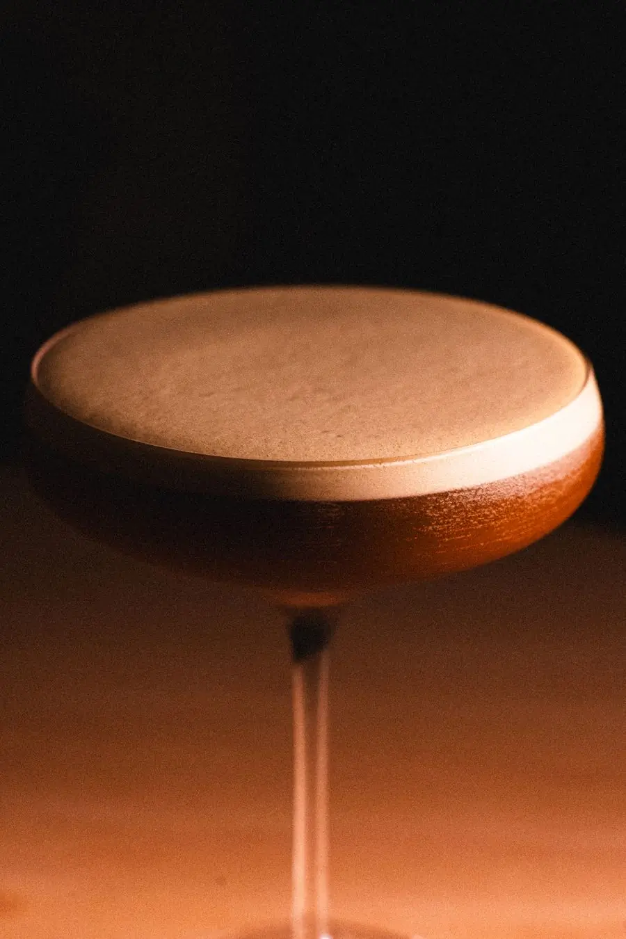 A frothy sour in the low light of the bar