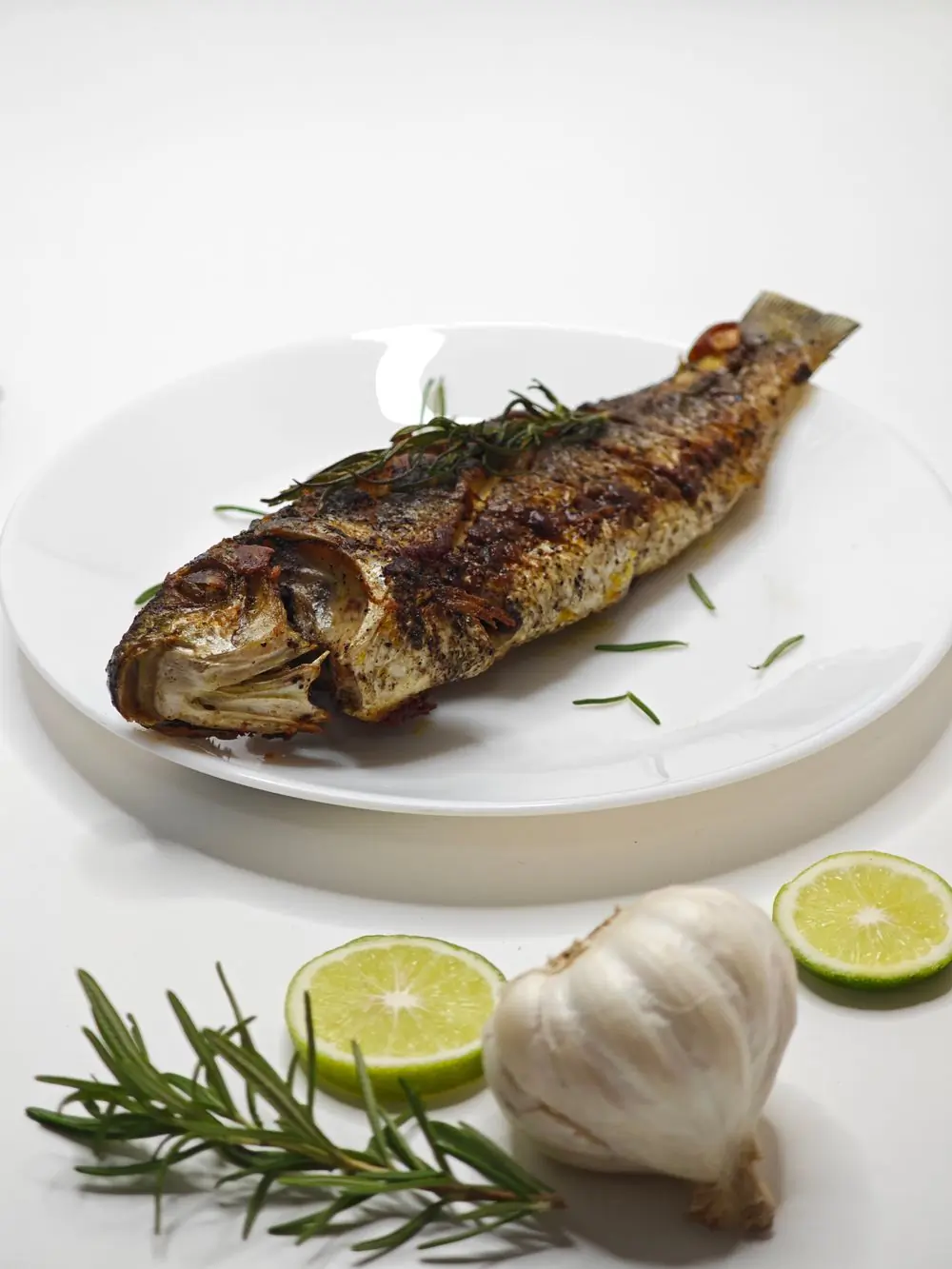 Whole grilled fish with rosemary and lime, plated for the pass