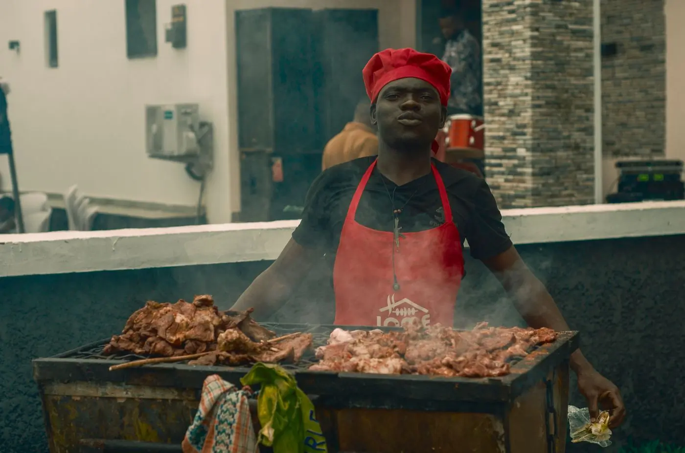 A cook turning meat over an open grill