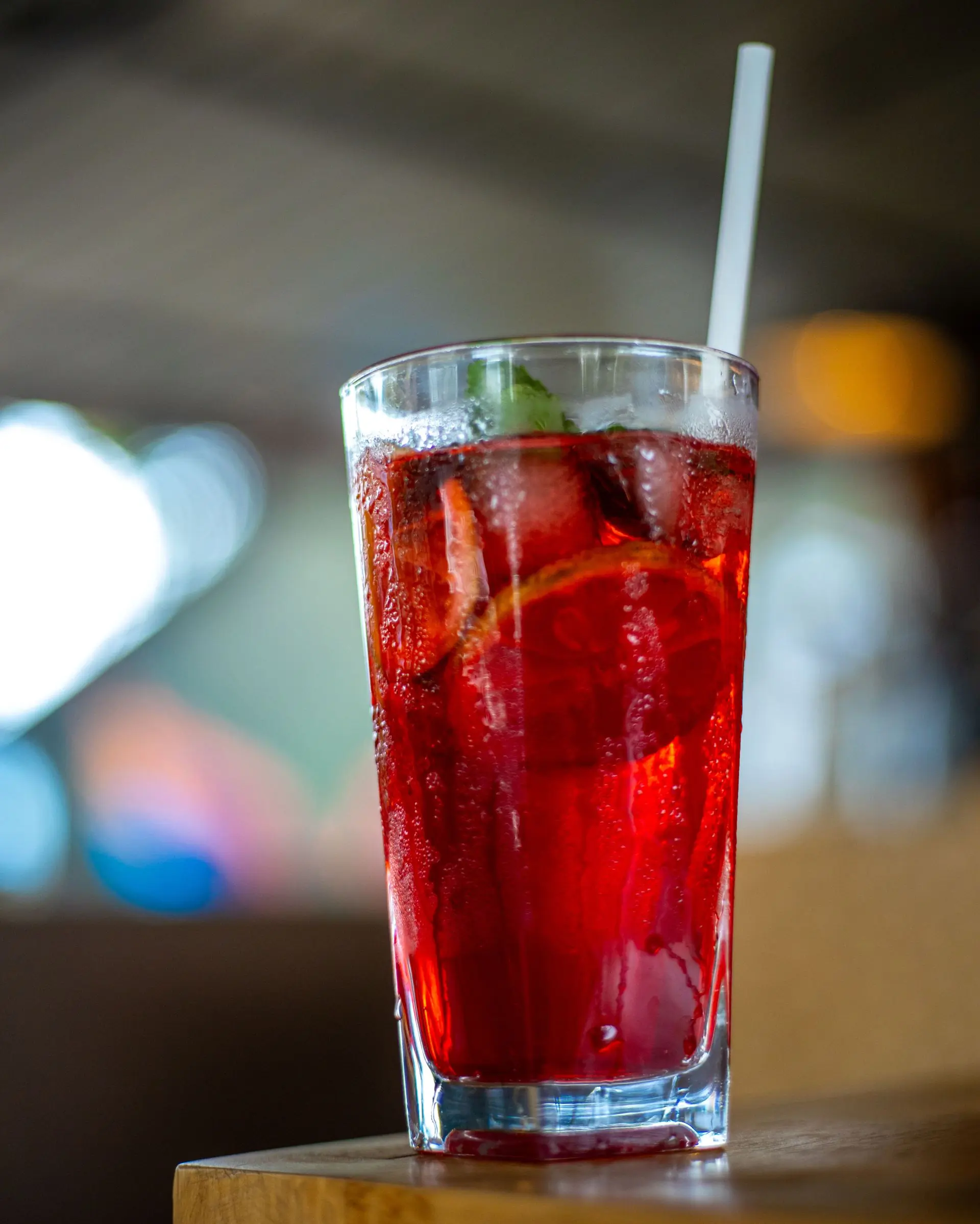 Two tall pink drinks dressed with fruit against a hot pink ground